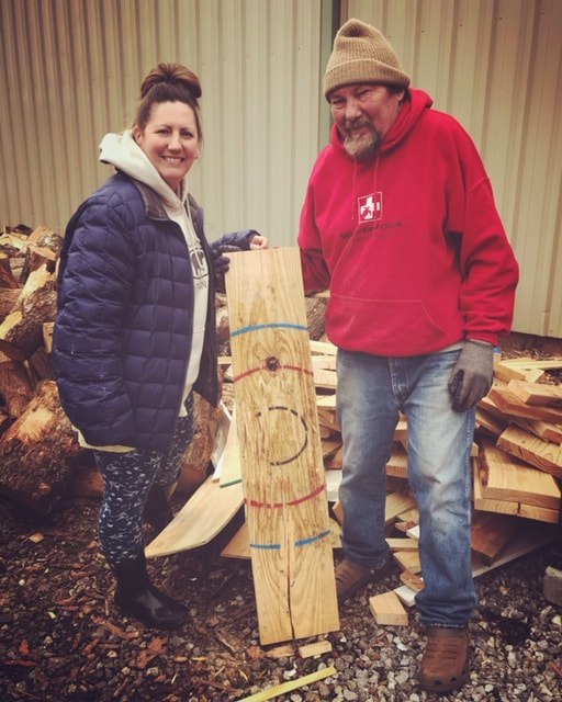 Man and woman making a target out of wood for axe throwing