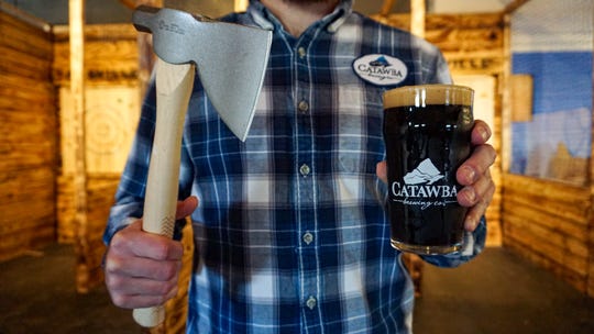 Man holding an axe and craft beer in his hands